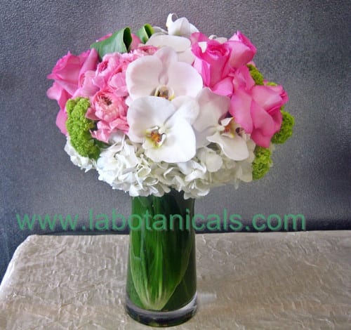 Pink and white bouquet in a tall green glass vase