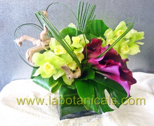 Bouquet of lime green orchids and purple calla lilies in a glass vase