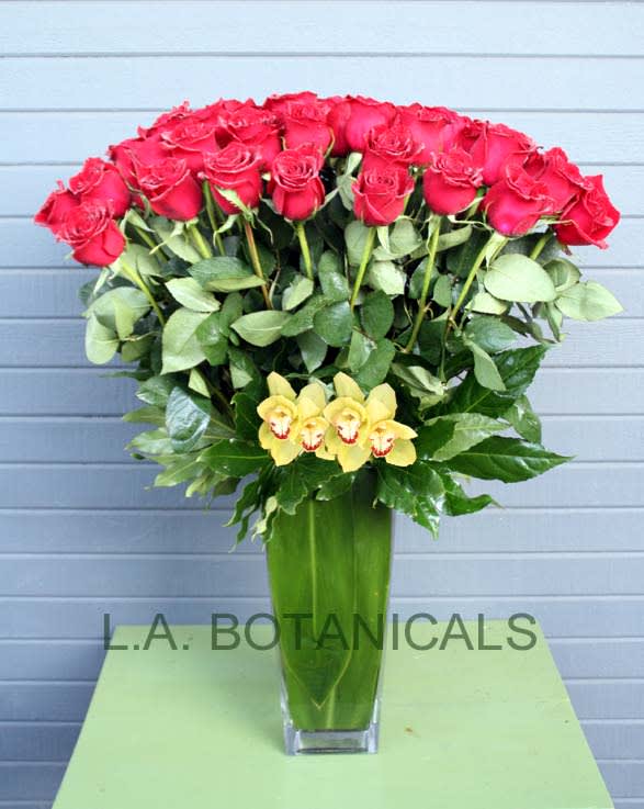 Tall vase arrangement of red roses with yellow orchids