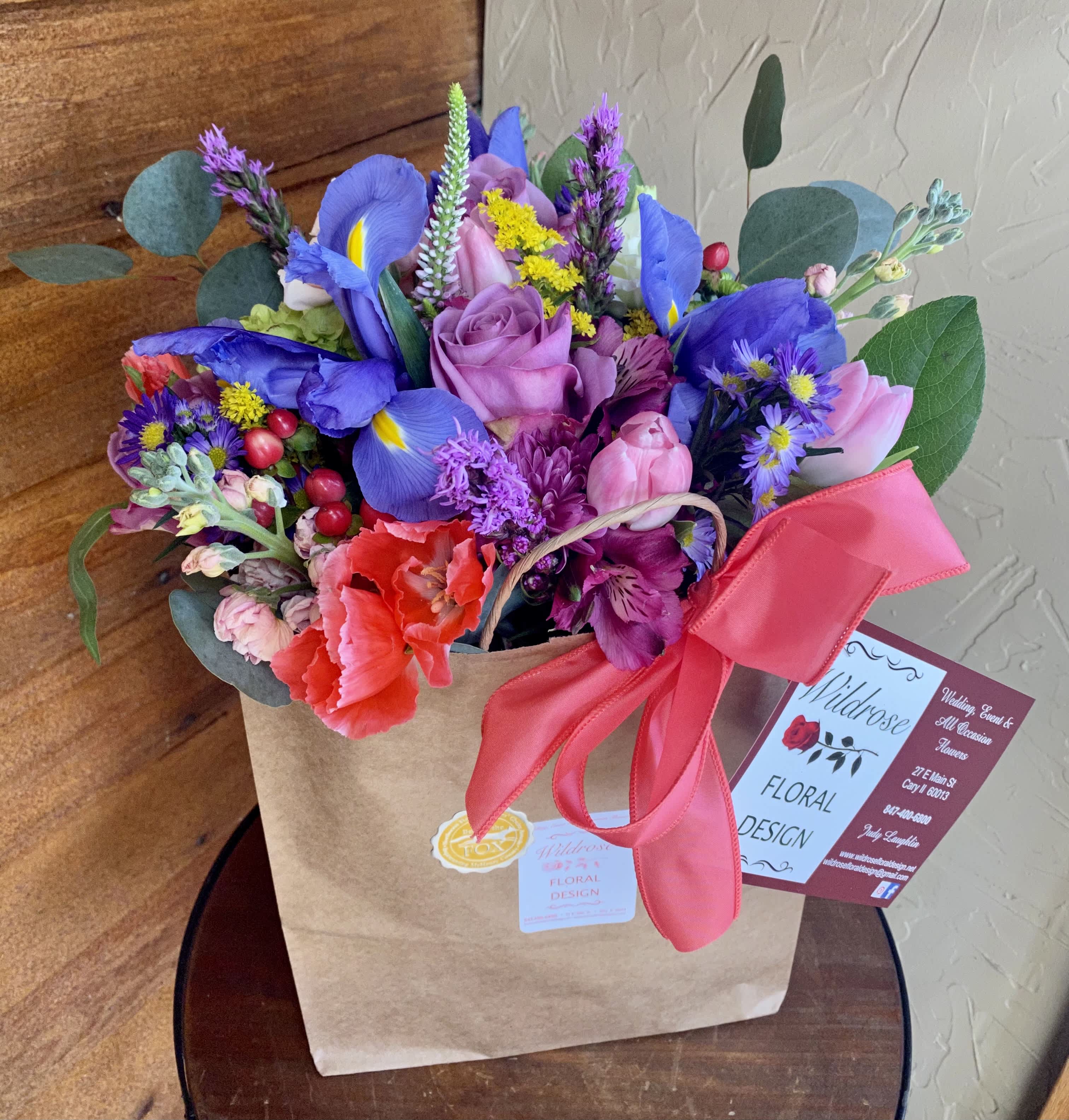 Colorful bouquet in a brown paper bag with a pink ribbon