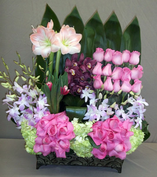 Pink roses and orchids arranged in a black rectangular container