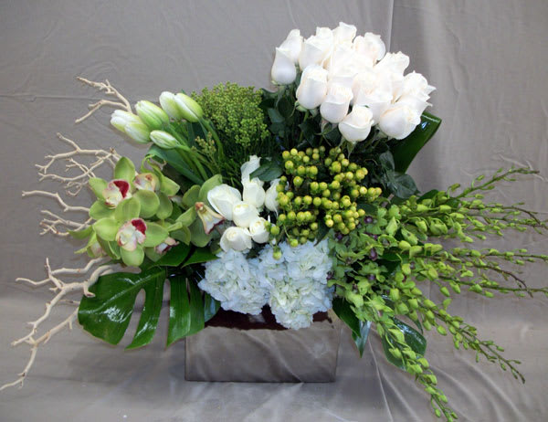 White floral arrangement with orchids and roses in a square vase