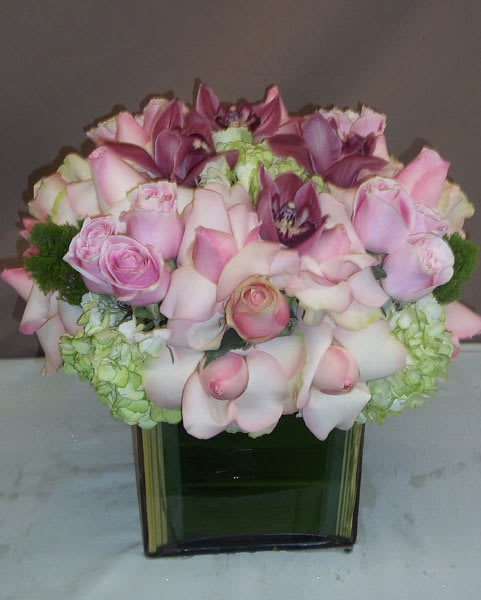 Pink roses and calla lilies arranged in a square glass vase