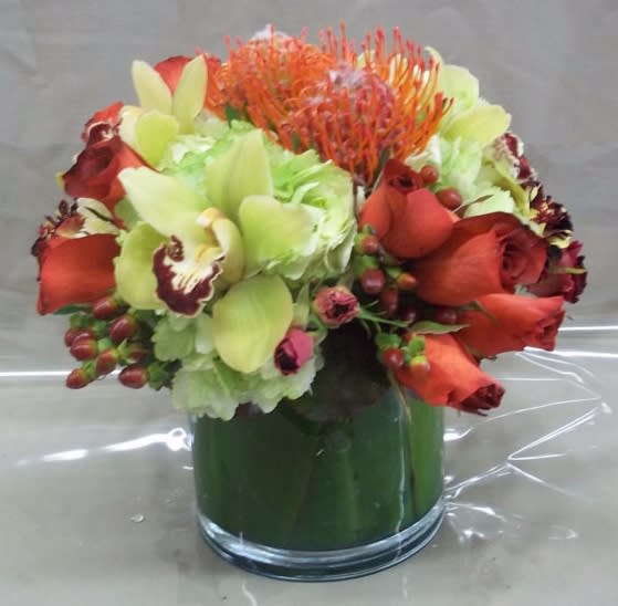 Orange and red floral arrangement in a glass vase