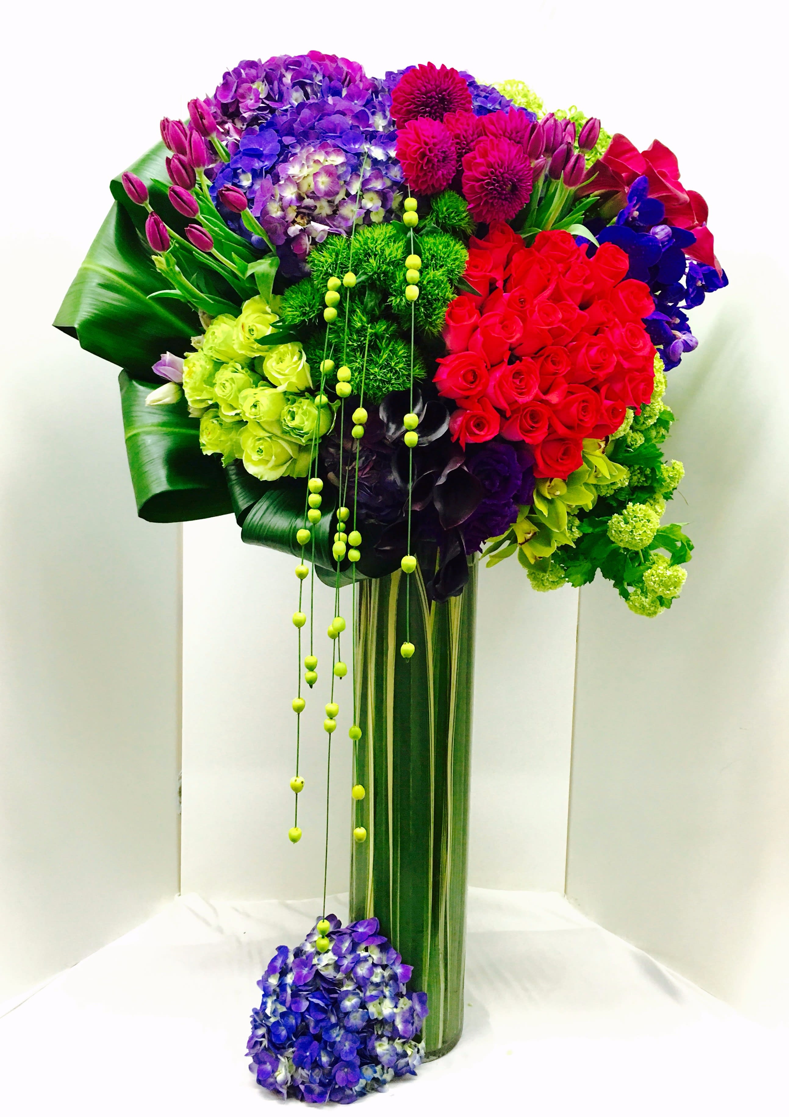 Tall bouquet of multicolored flowers in a glass vase with hanging beads
