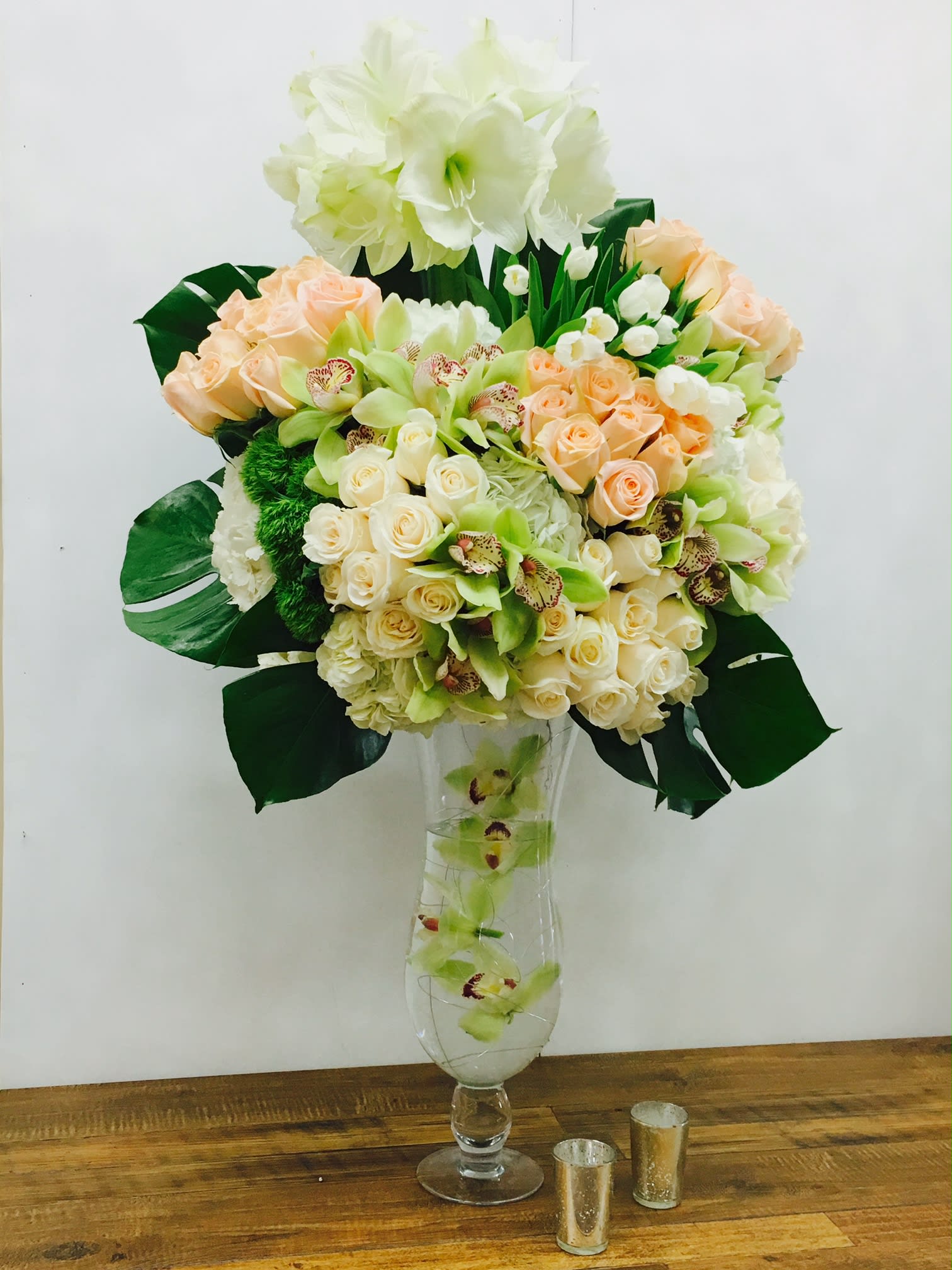 Tall bouquet of cream and peach flowers in a clear glass vase