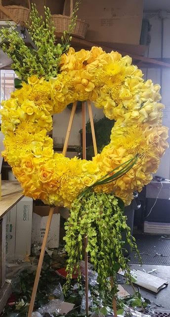 Yellow floral wreath on a wooden easel with trailing greenery