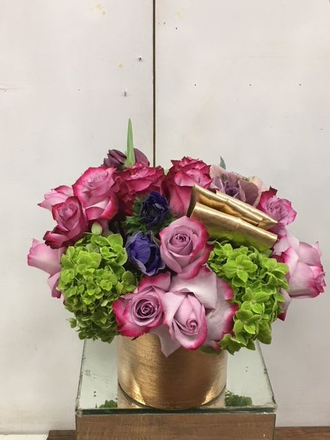 Pink and purple roses with green hydrangeas in a gold container