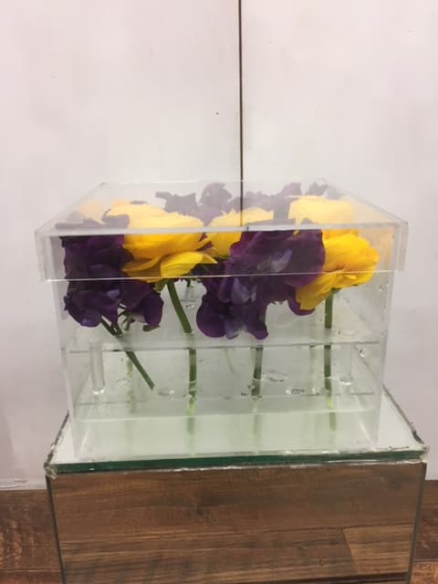 Purple and yellow flowers arranged in a clear acrylic box