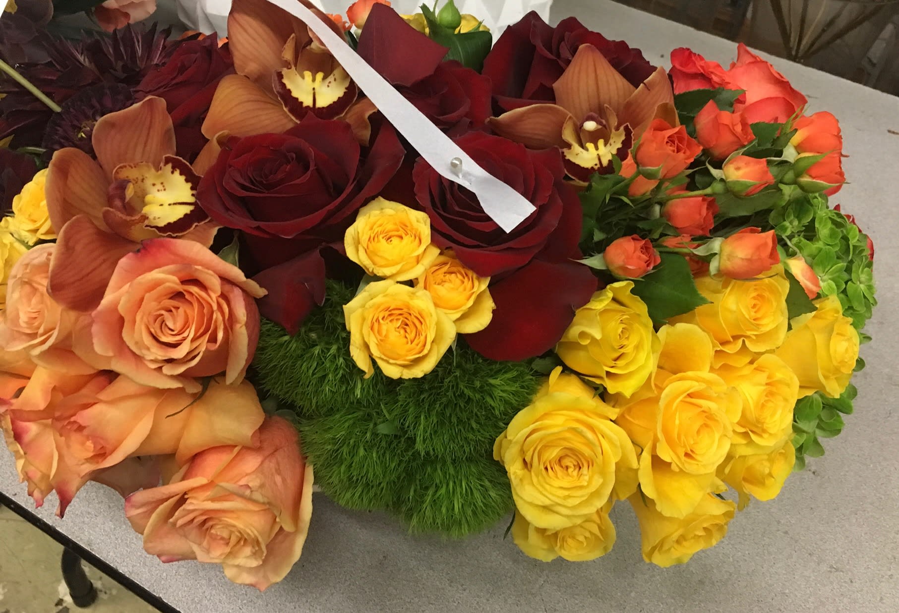 Mixed bouquet of roses and orchids in red, peach, yellow, and orange