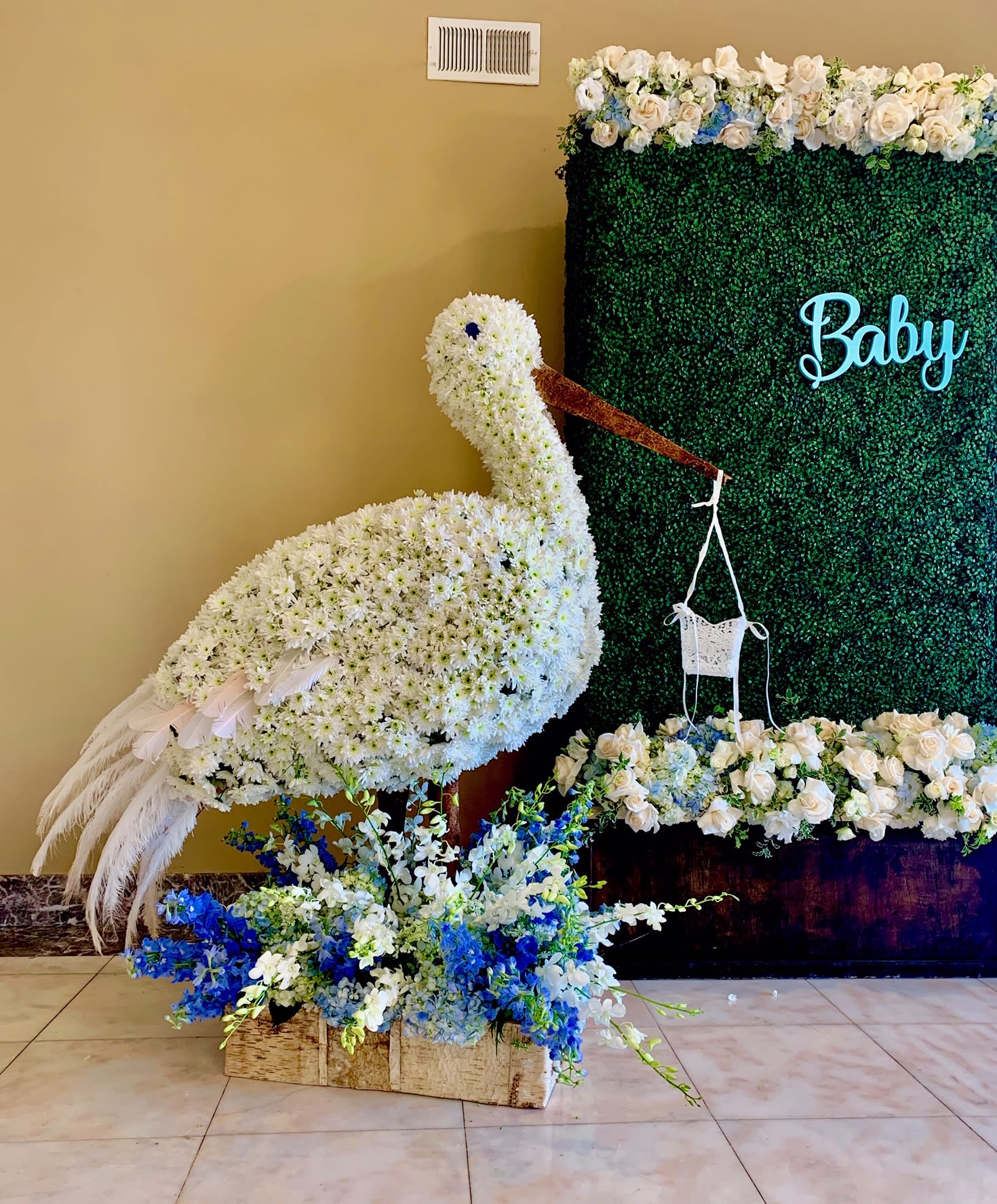 White floral swan display beside a green backdrop with blue flowers