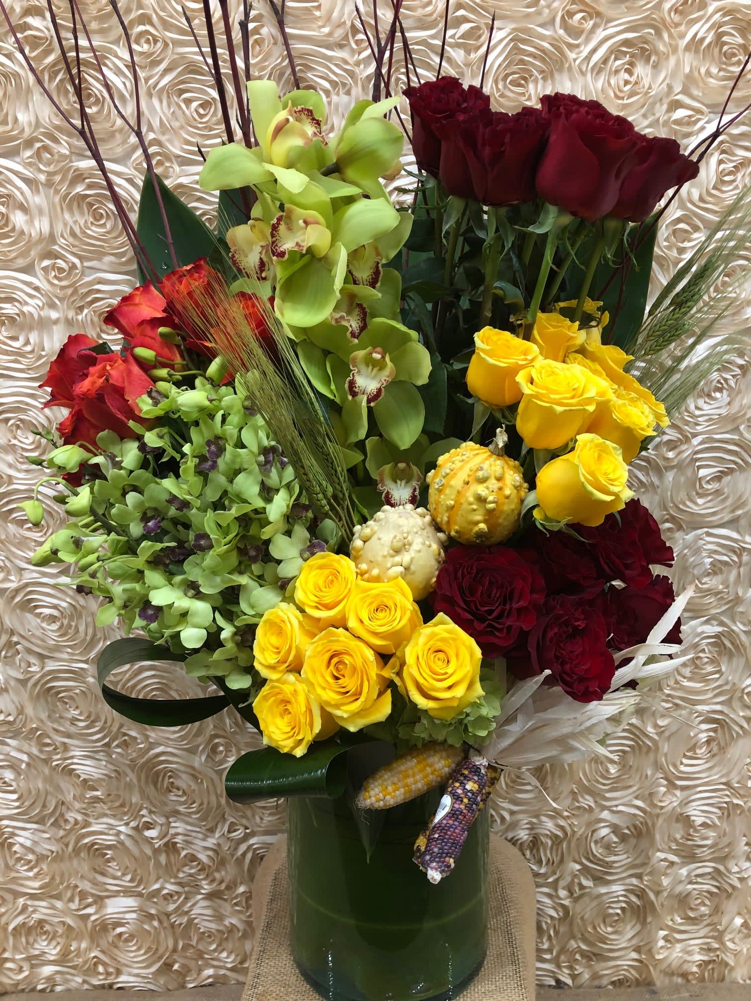 Mixed bouquet of roses and orchids in a tall green vase