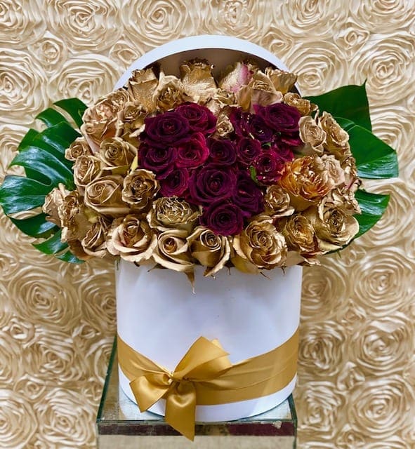 Bouquet of deep red and gold roses in a white hat box with a gold ribbon