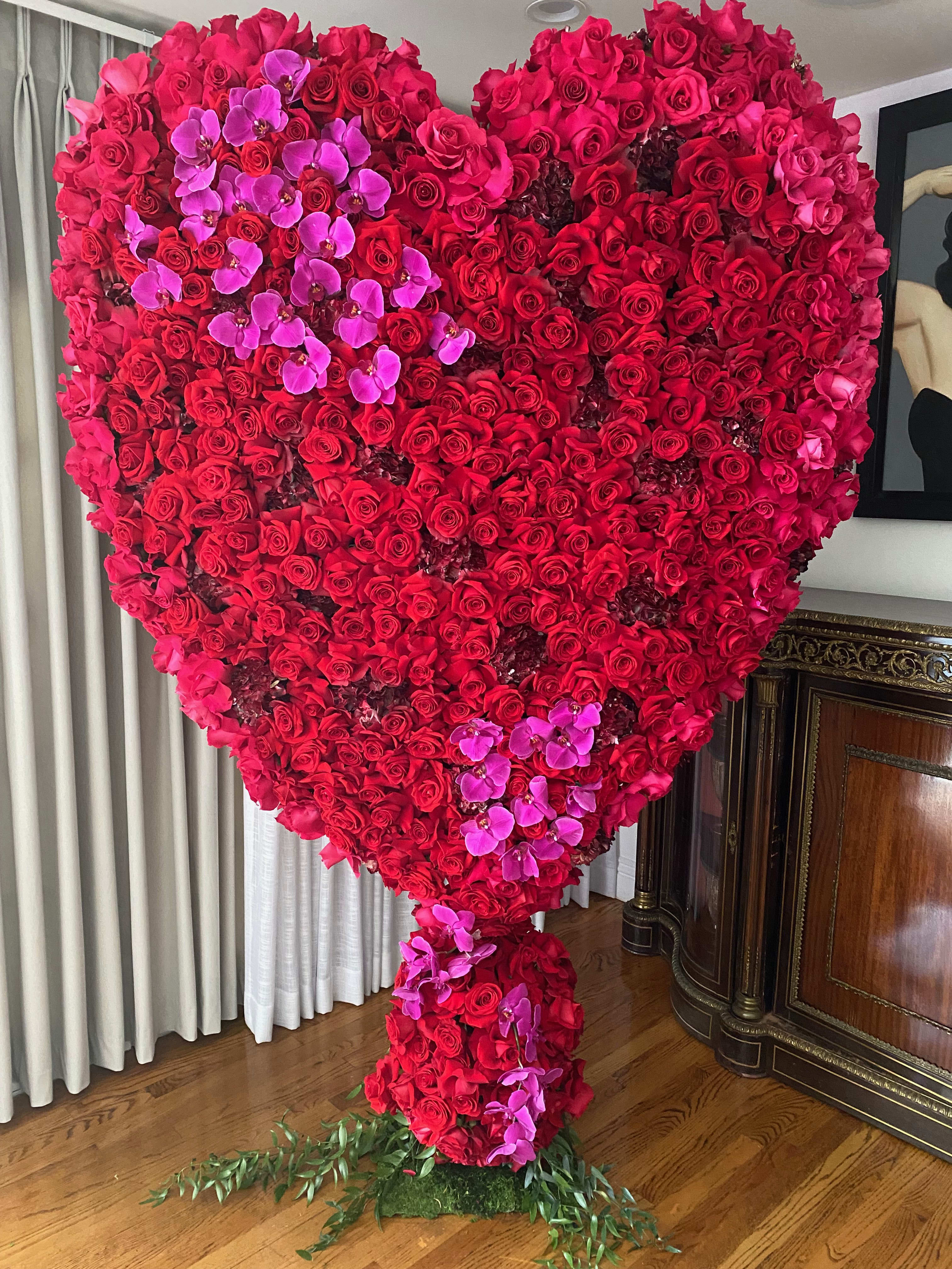 Large heart-shaped arrangement of red roses with pink orchids