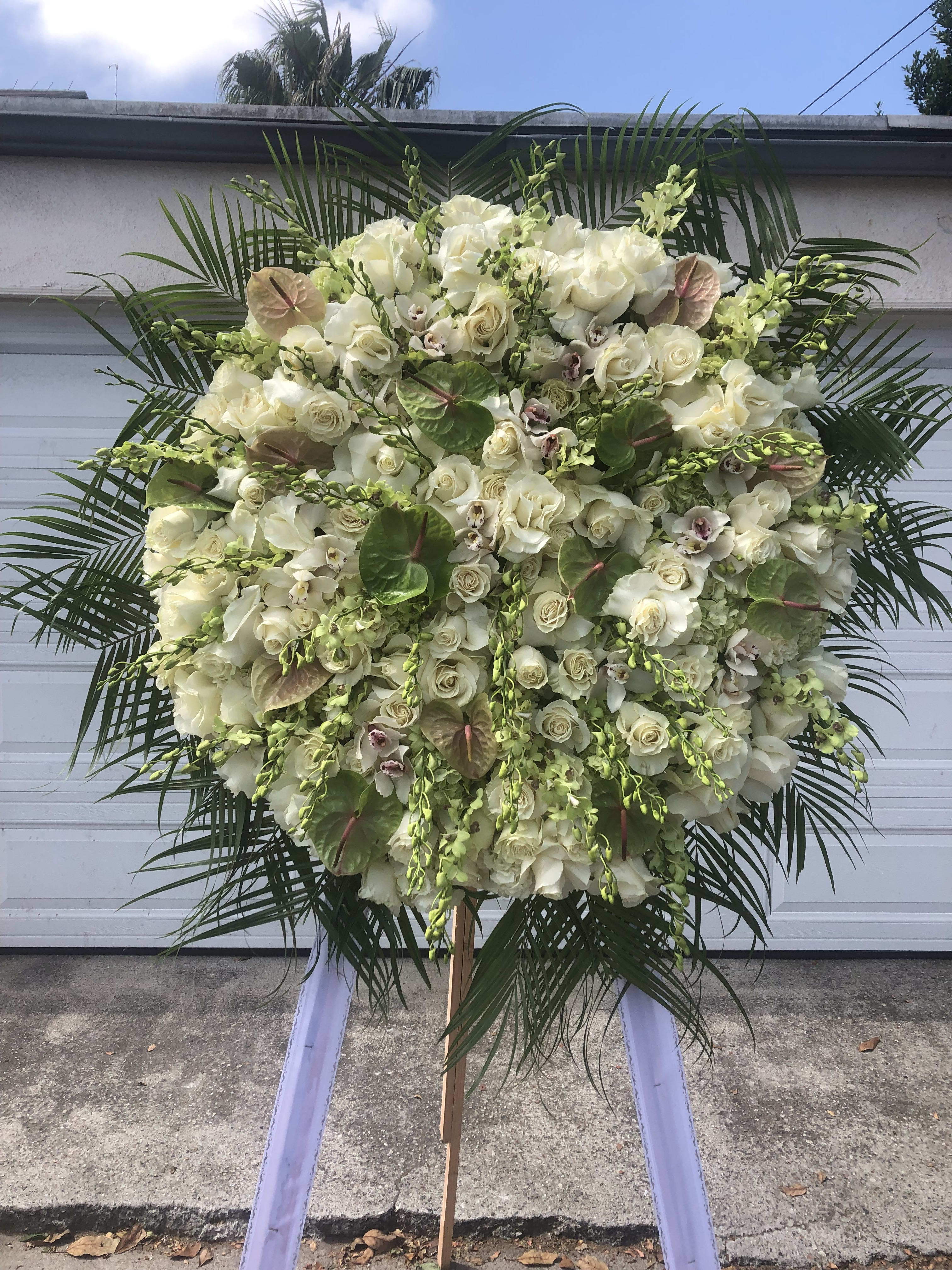 Large white floral standing spray with palm fronds and orchids