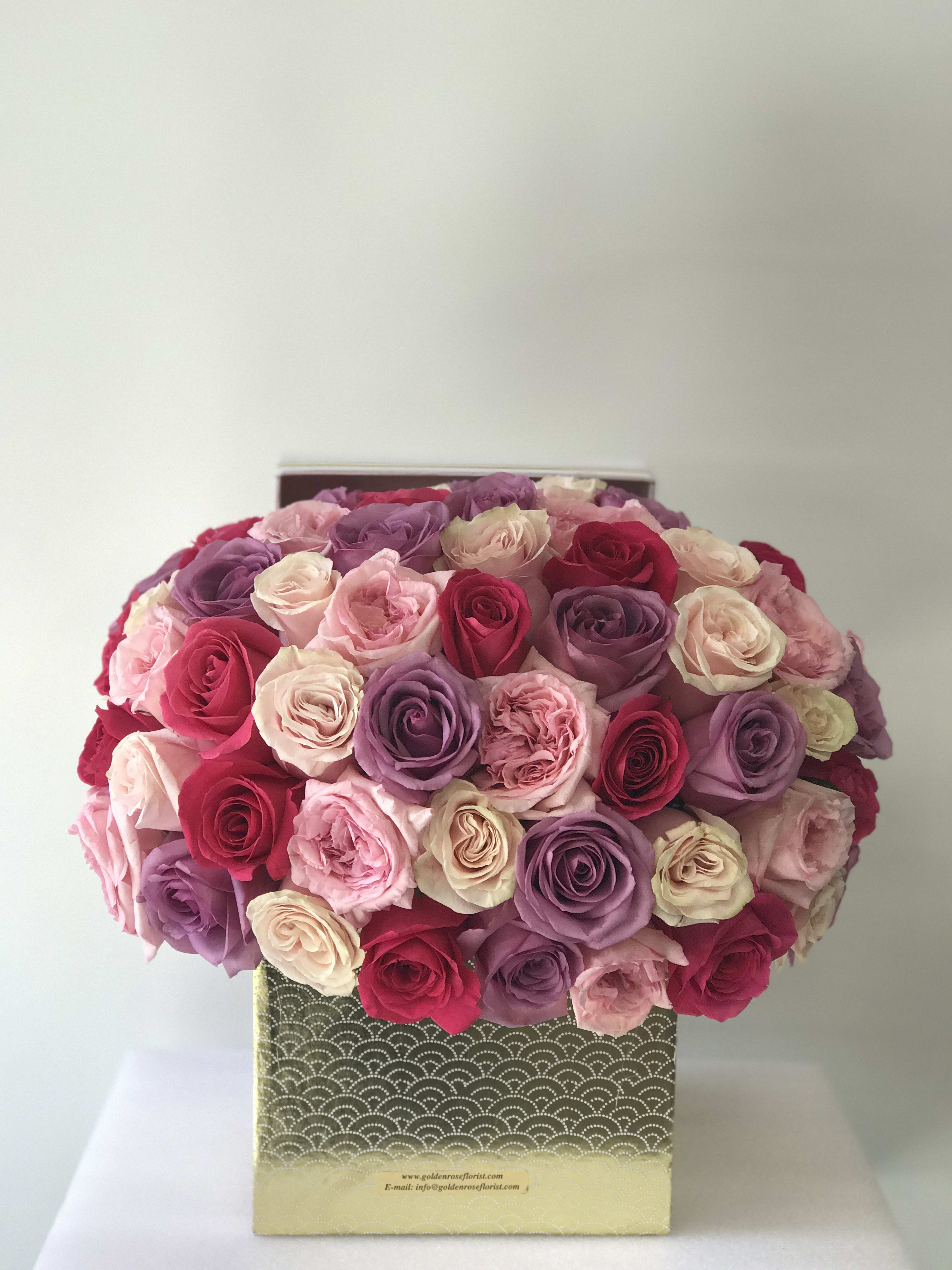 Boxed bouquet of pink, purple, and cream roses