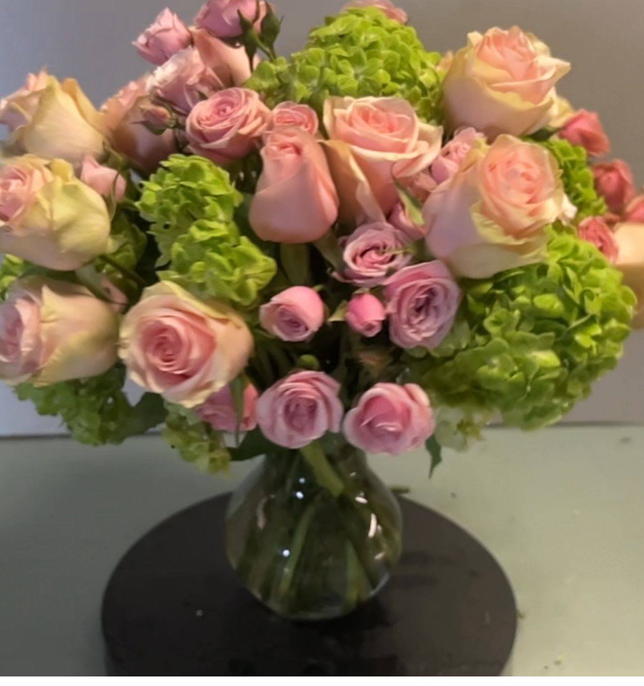 Pink roses and green hydrangeas in a glass vase