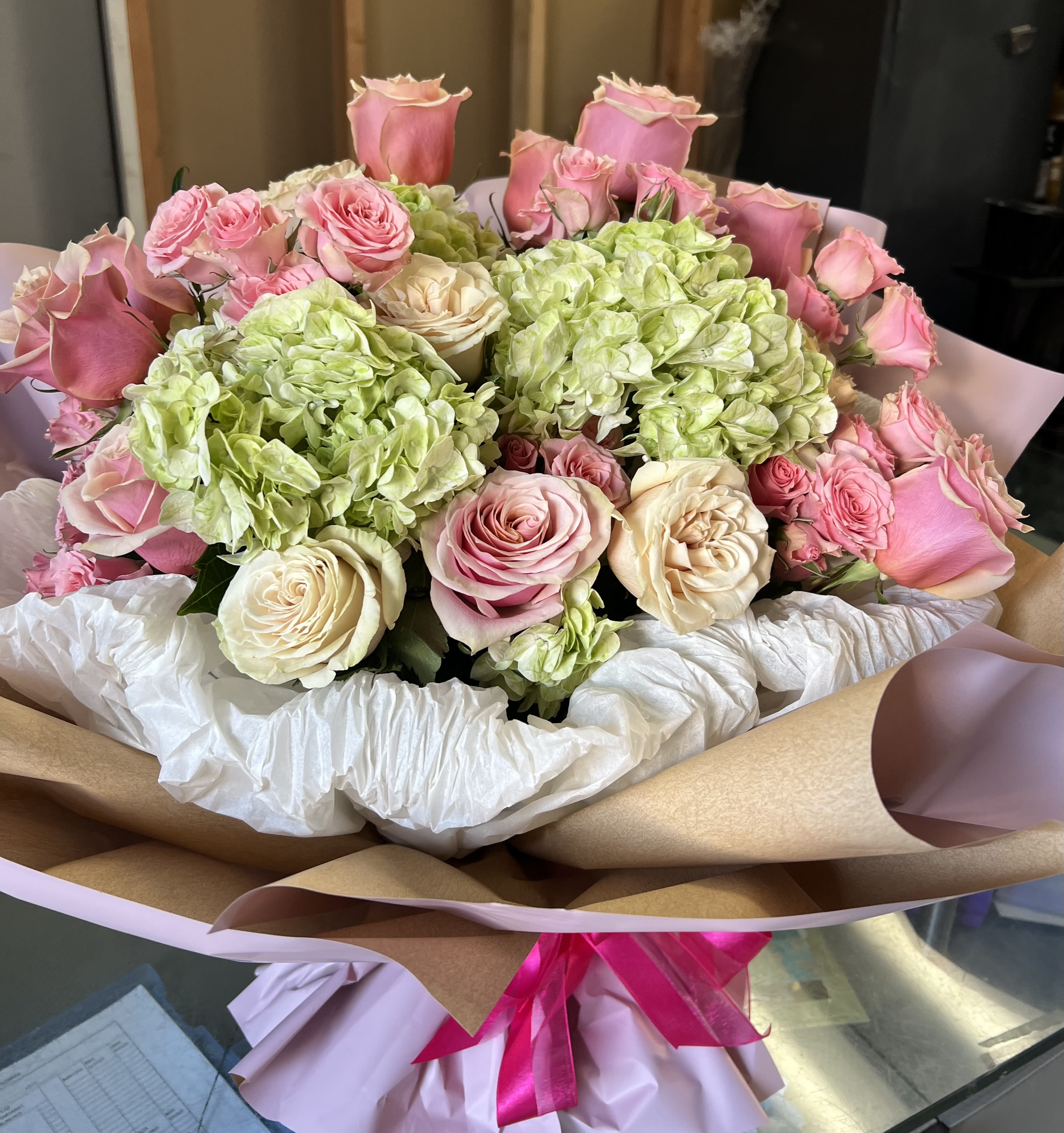 Bouquet of pink and cream roses with green hydrangeas wrapped in paper