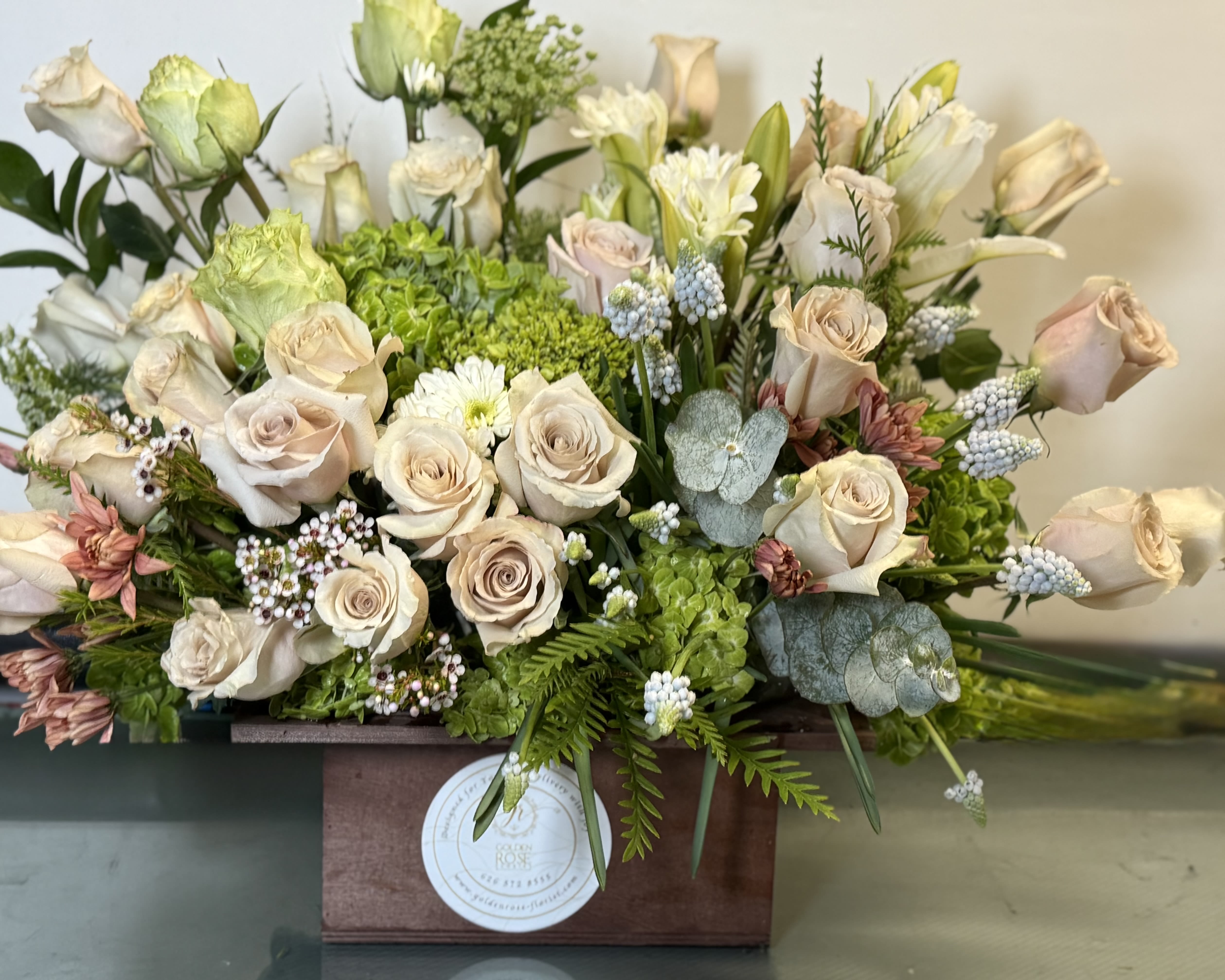 Cream roses and green hydrangeas in a wooden box arrangement