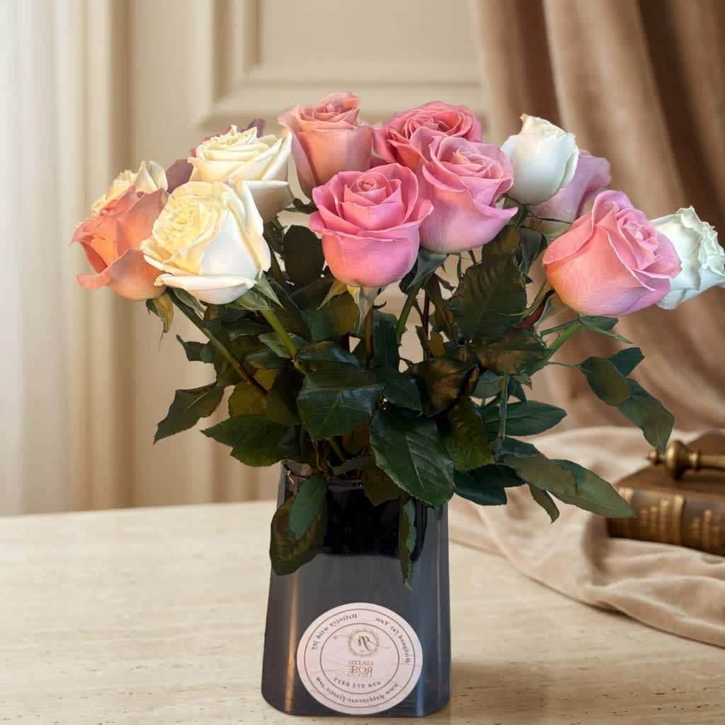 Pink and white roses arranged in a dark vase on a table