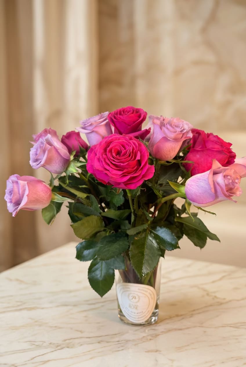 Pink and lavender roses arranged in a clear glass vase