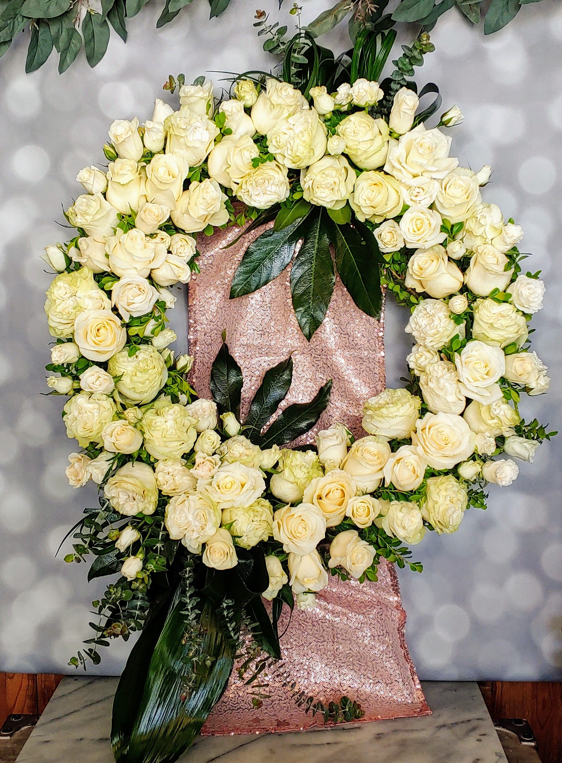 Large white rose wreath on a pink sequined stand