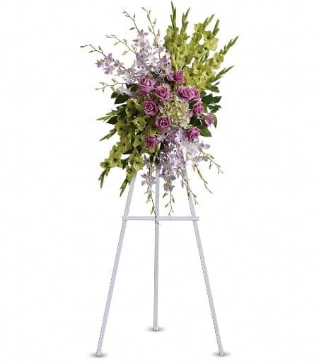 Standing floral spray with purple roses and green orchids on an easel