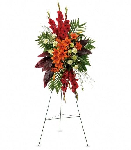 Tall floral standing spray with red and orange flowers on a metal easel