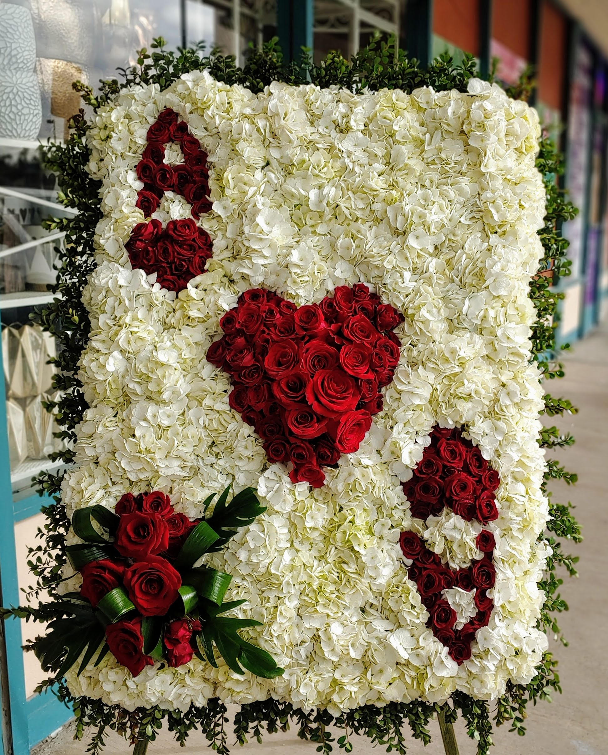 Large floral display of white hydrangeas with red rose hearts