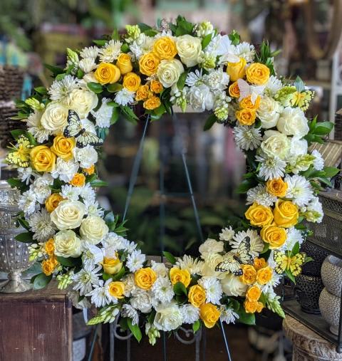 Large floral wreath with yellow and white roses and white daisy-like flowers