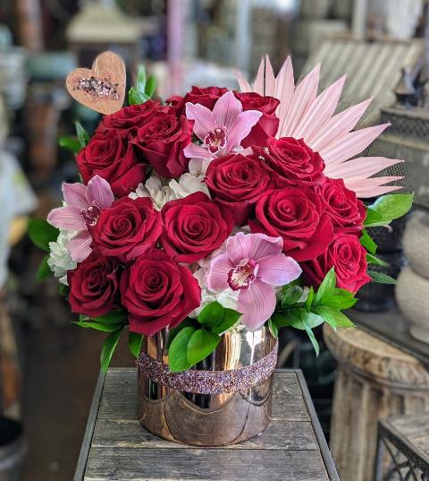 Bouquet of red roses and pink orchids in a metallic vase