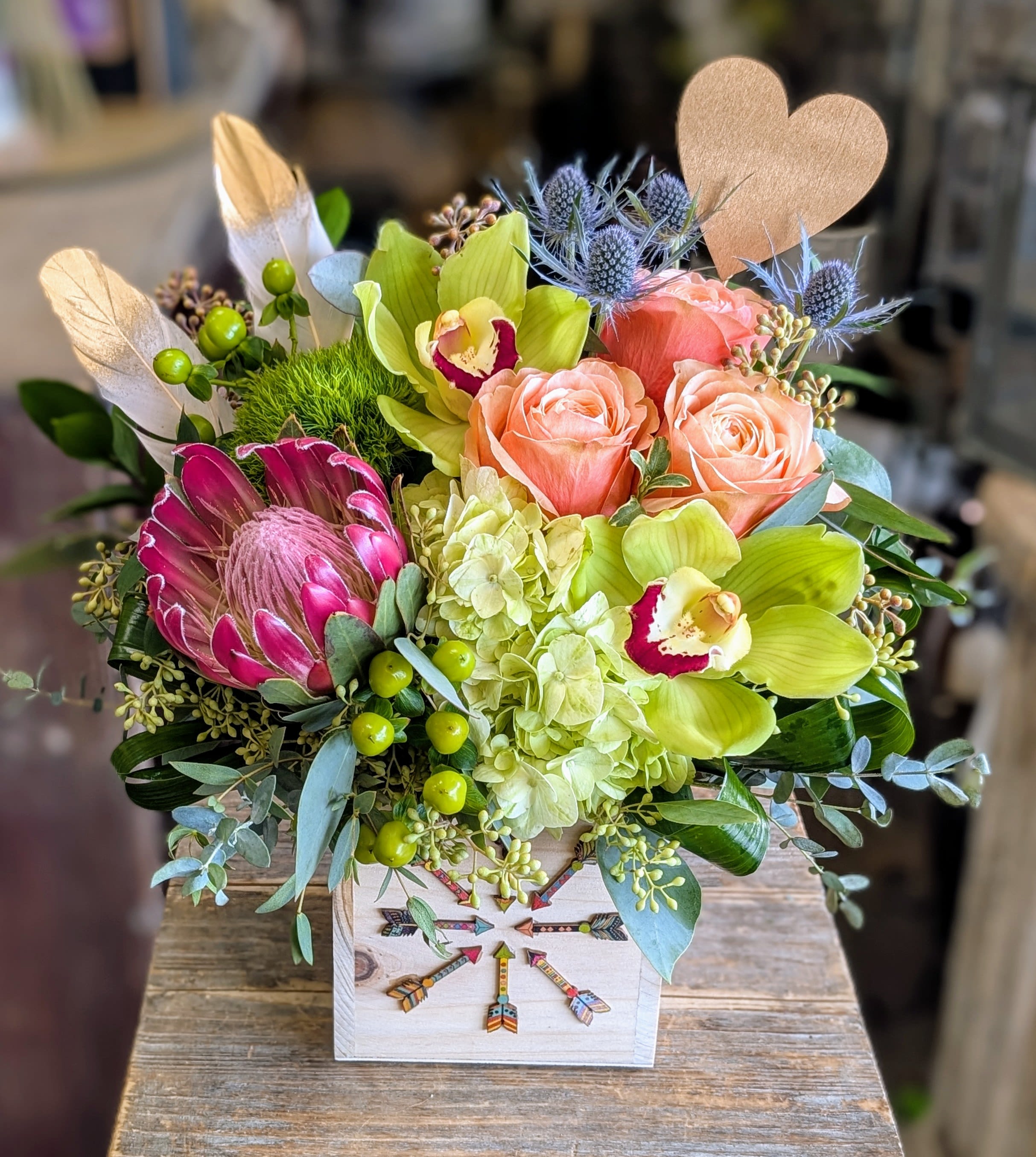 Mixed bouquet with peach roses, green orchids, and a protea in a decorative box
