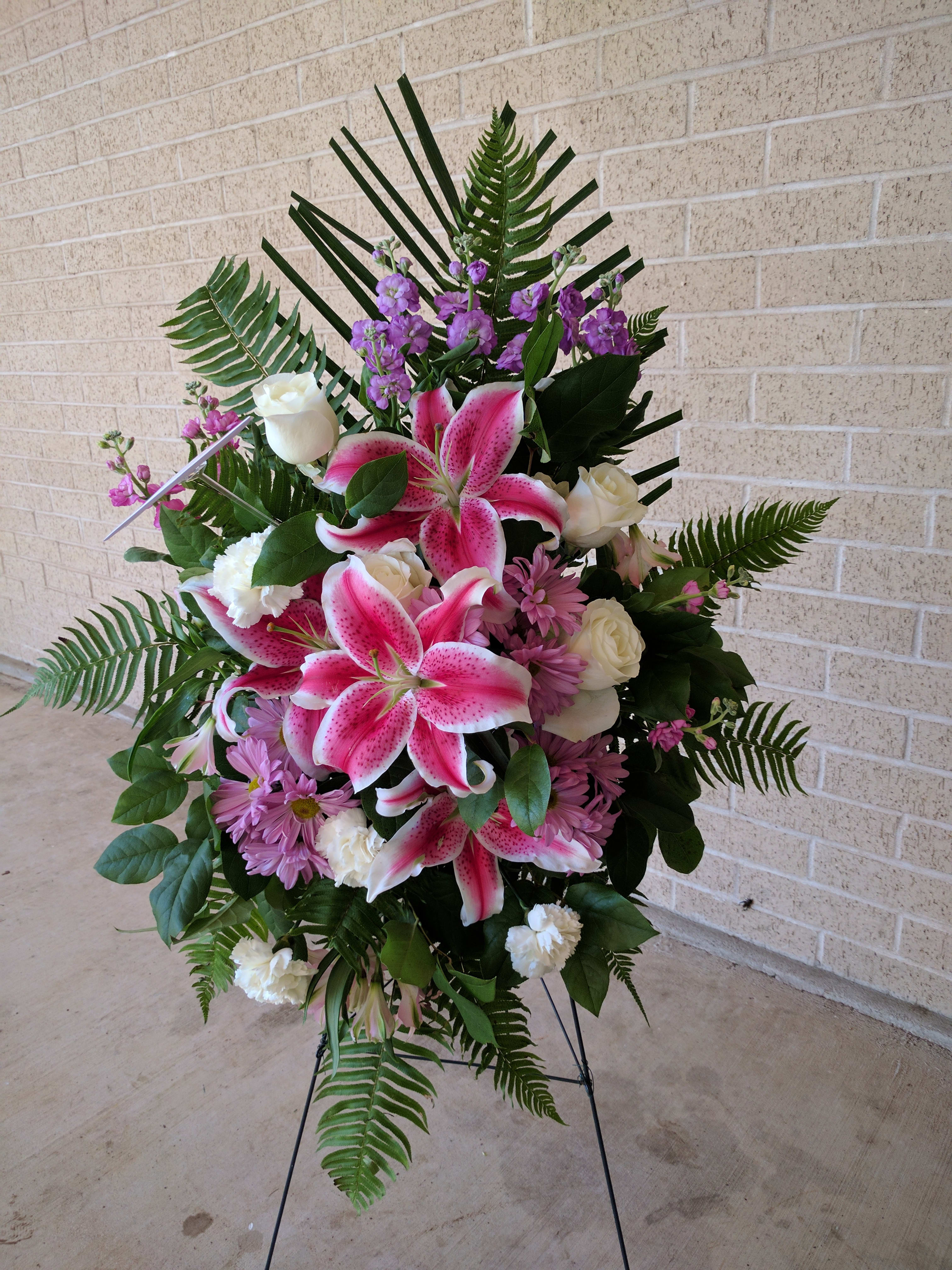 Standing spray with pink lilies, white roses, and purple flowers