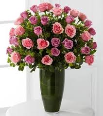 Pink and lavender roses arranged in a tall green vase