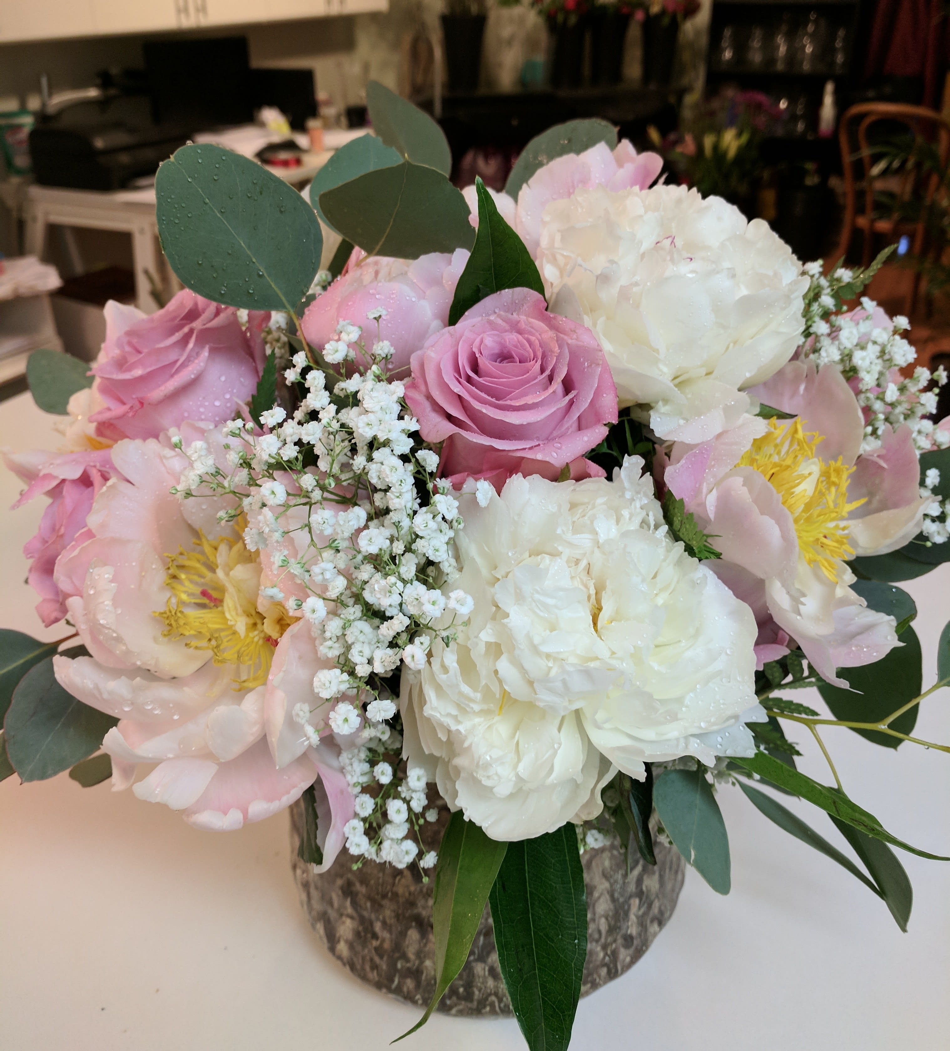 Pink and white bouquet with roses and peonies in a rustic vase