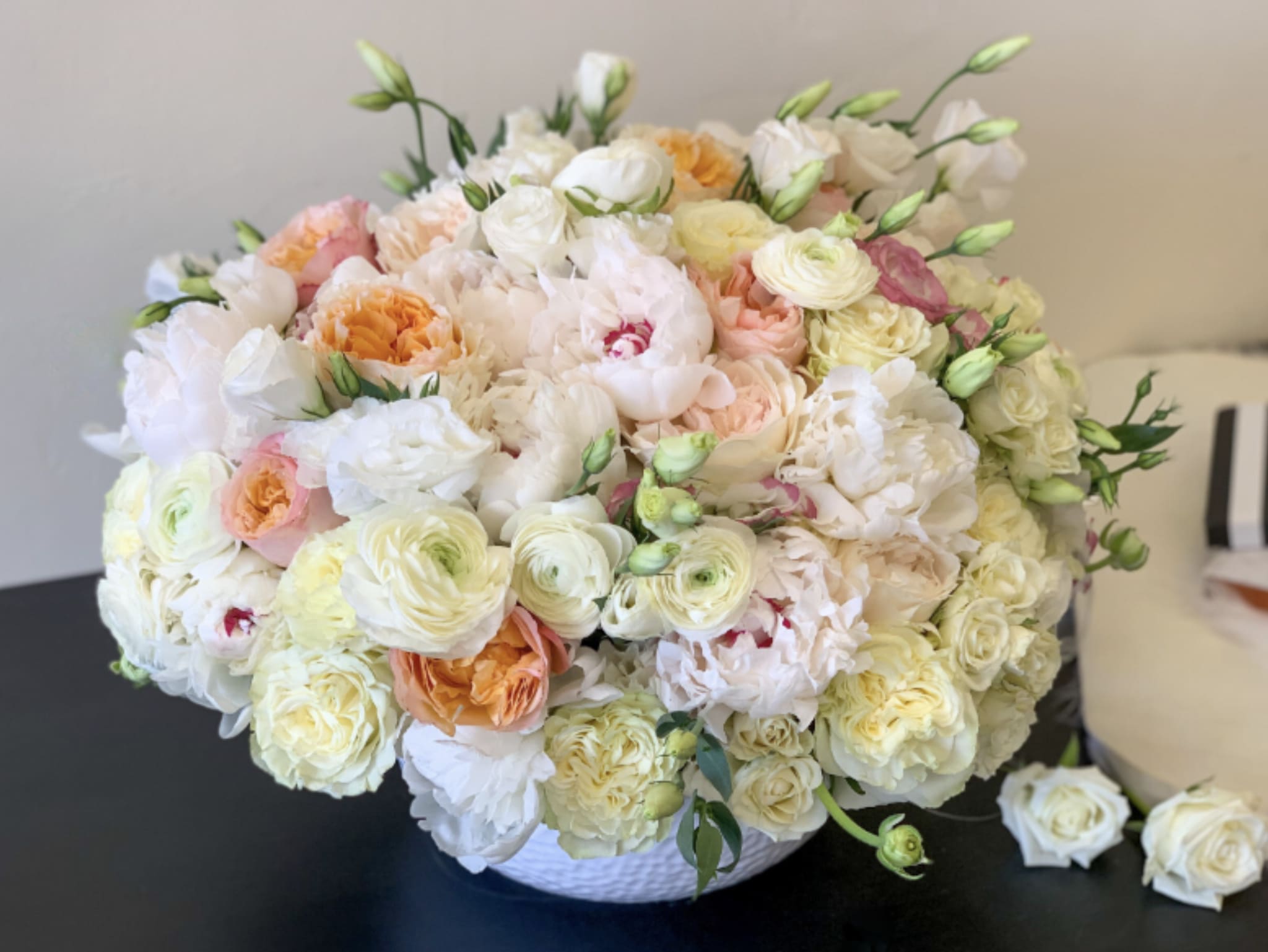 Large pastel bouquet of roses and ranunculus in a white basket