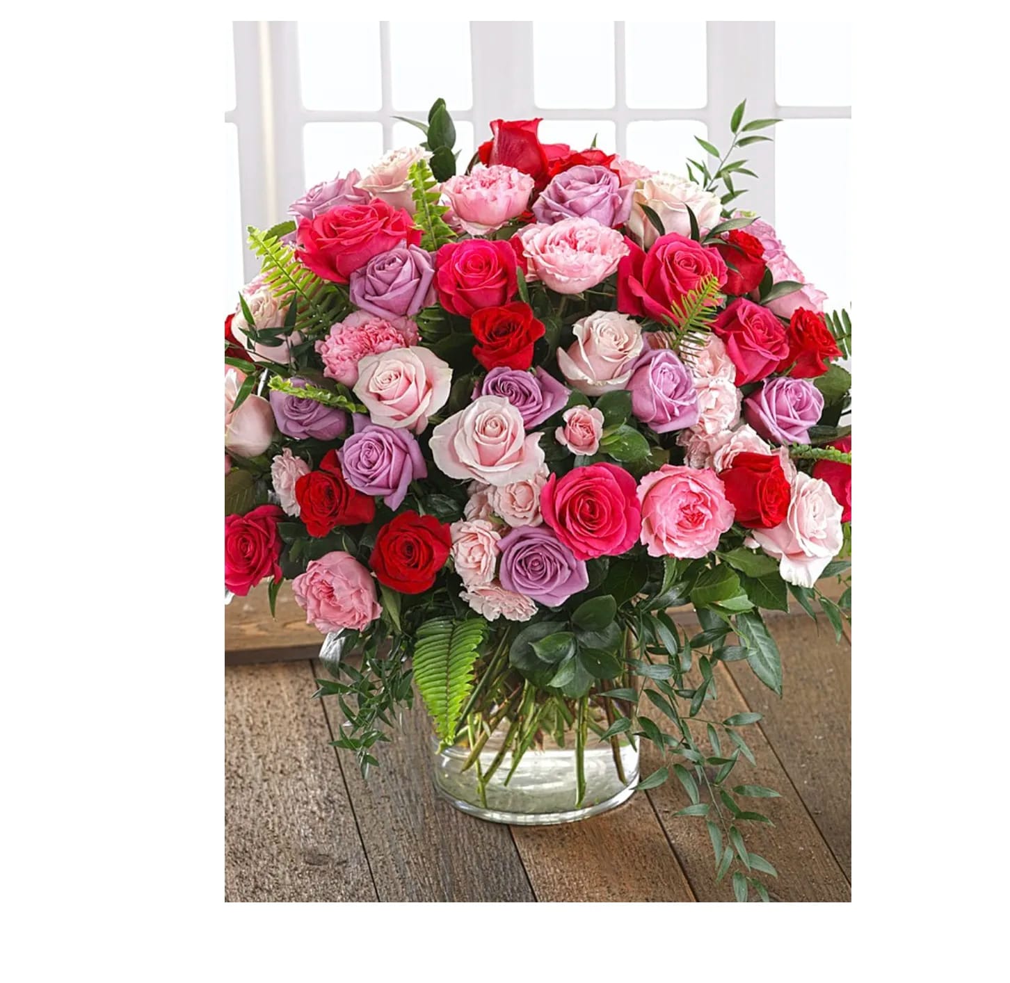 Mixed pink, red, and lavender roses in a clear glass vase