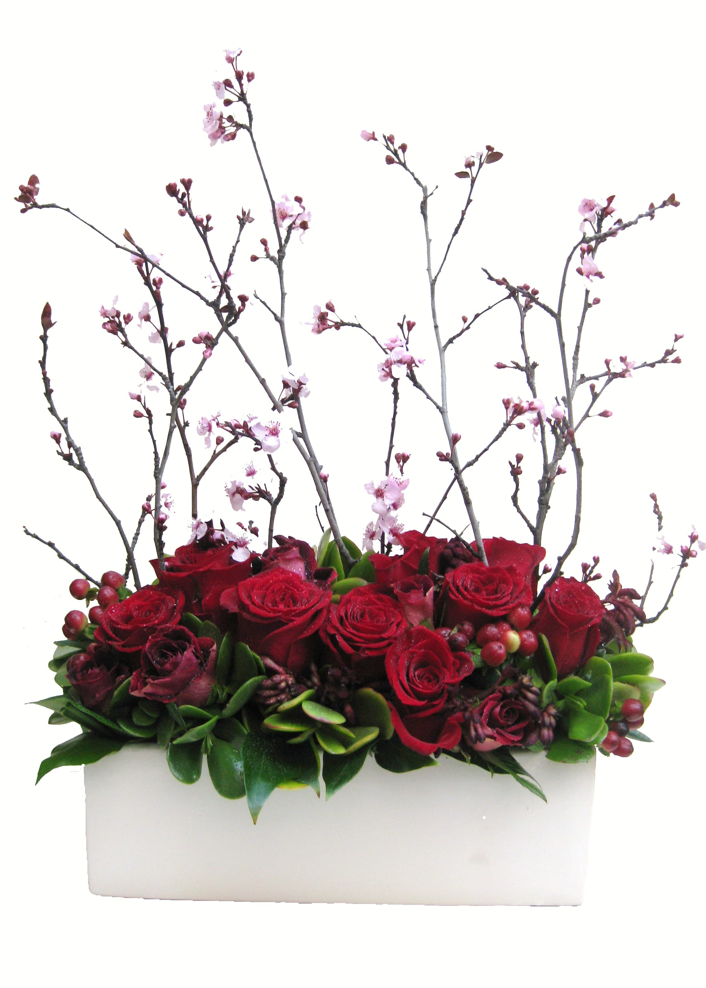 Red roses and pink blossoms arranged in a white rectangular container