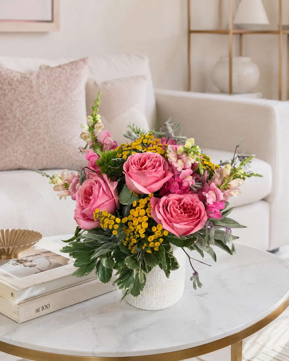 Pink roses and yellow filler flowers in a white vase on a coffee table