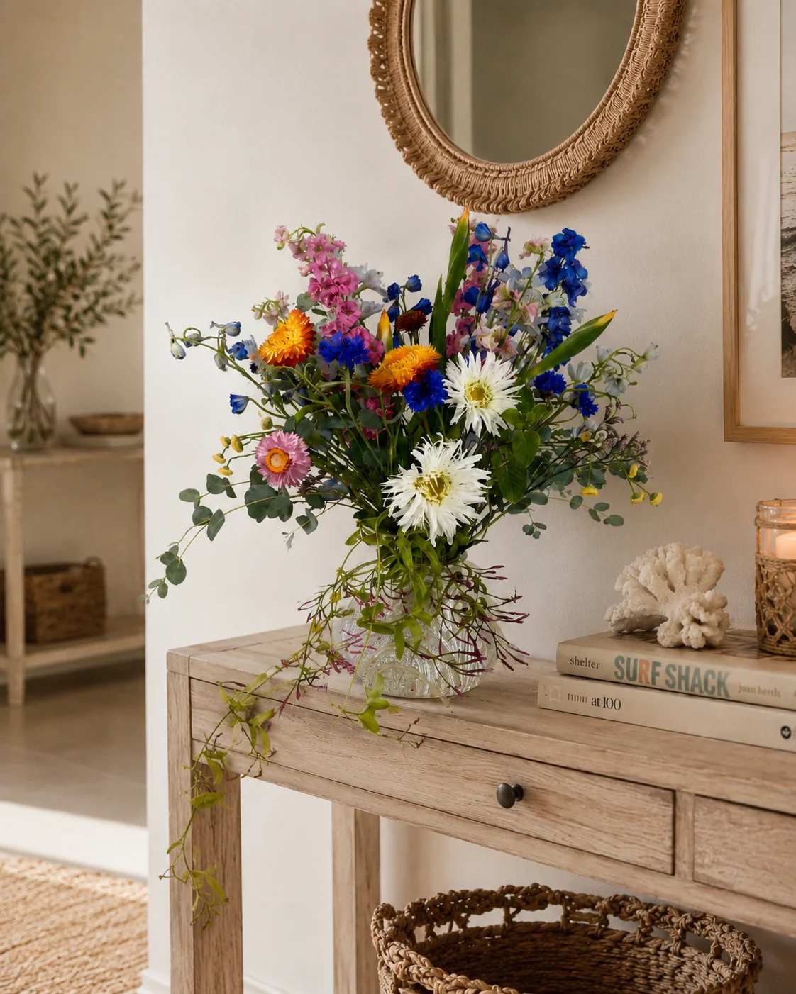 Mixed bouquet of colorful flowers in a clear glass vase on a wooden table