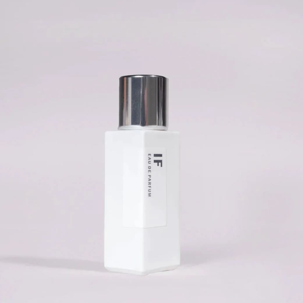 White perfume bottle with a silver cap on a pale background