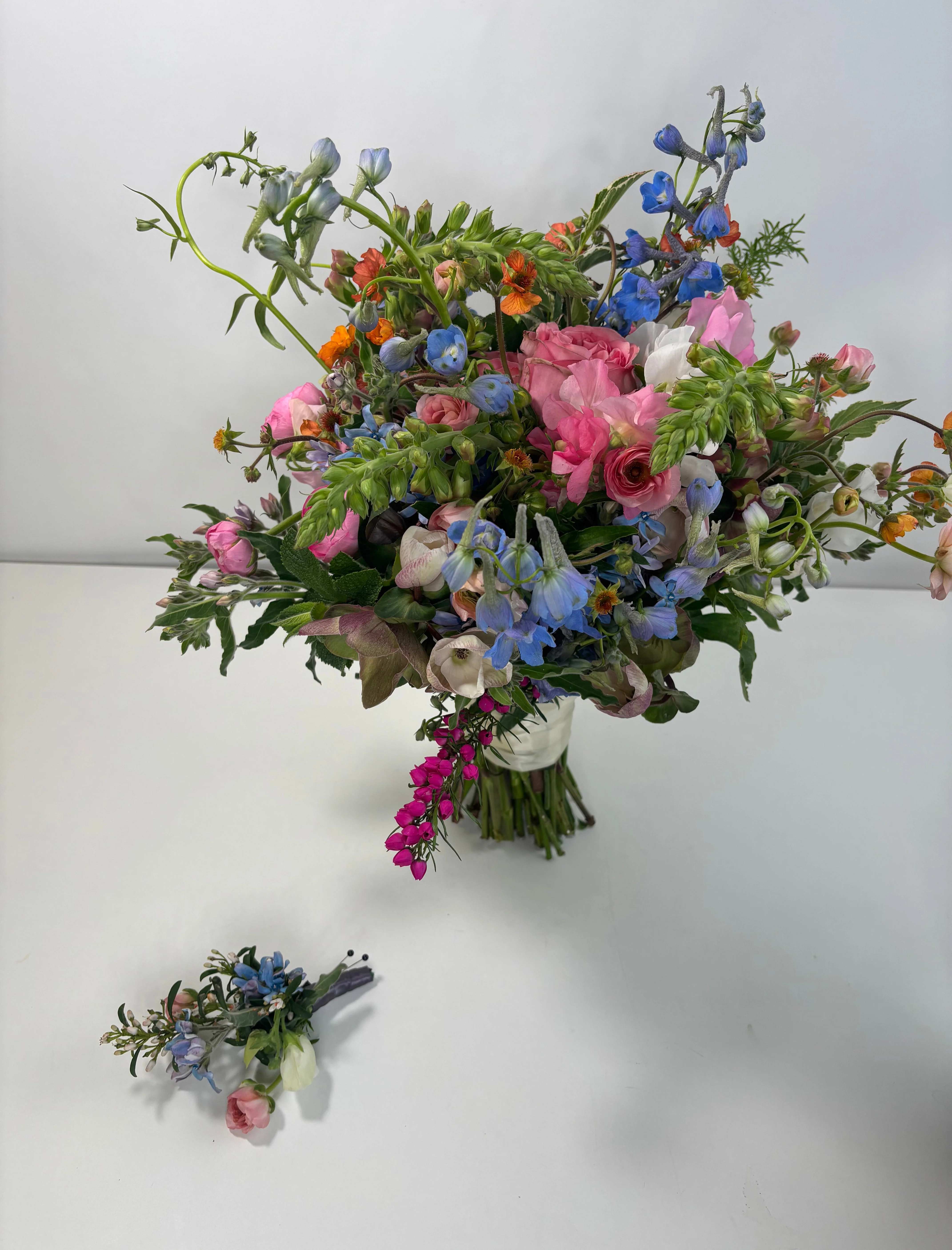 Loose bouquet of pink, blue, and white flowers in a clear vase