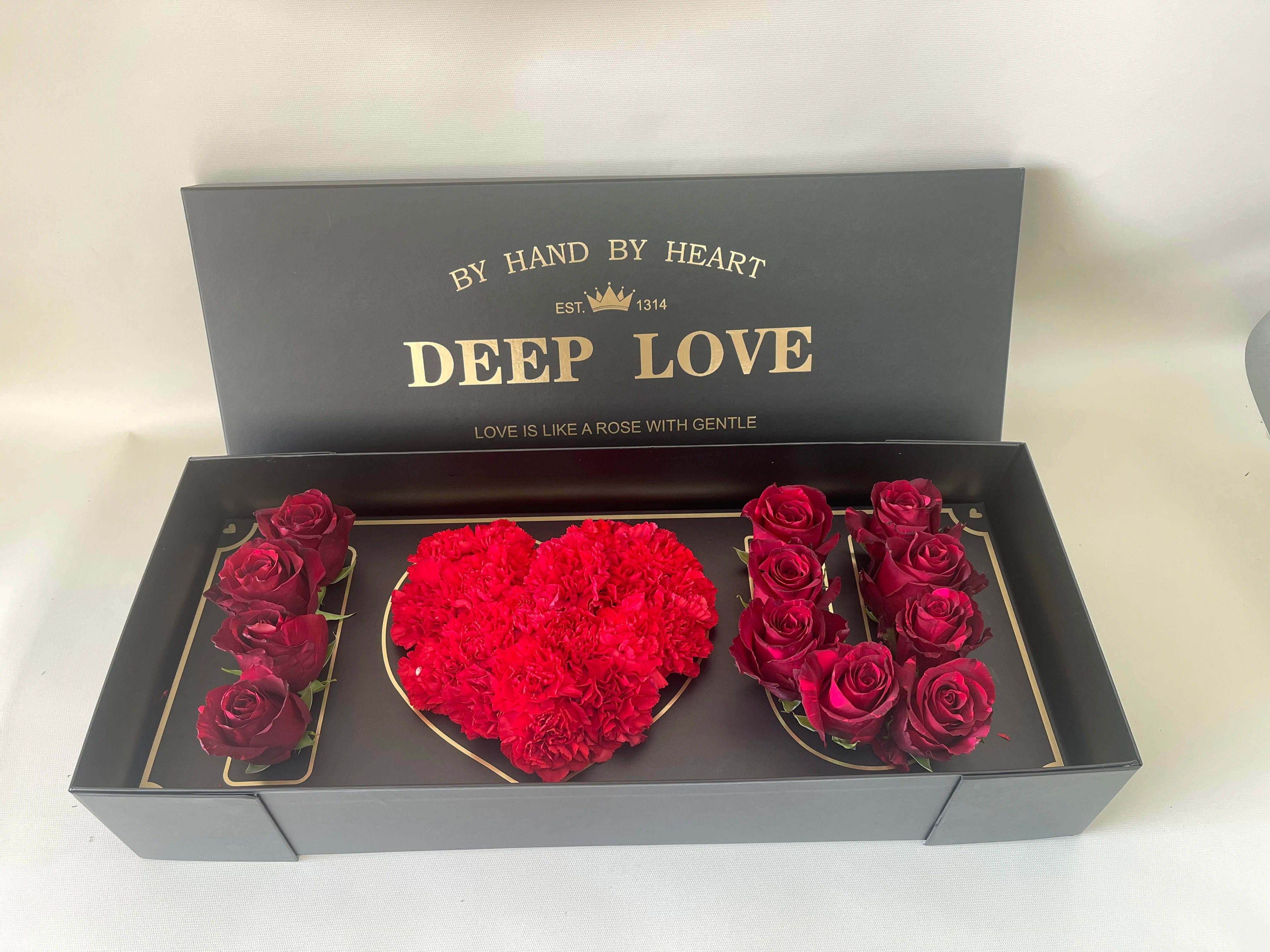 Boxed arrangement of red roses and a heart-shaped cluster of red carnations
