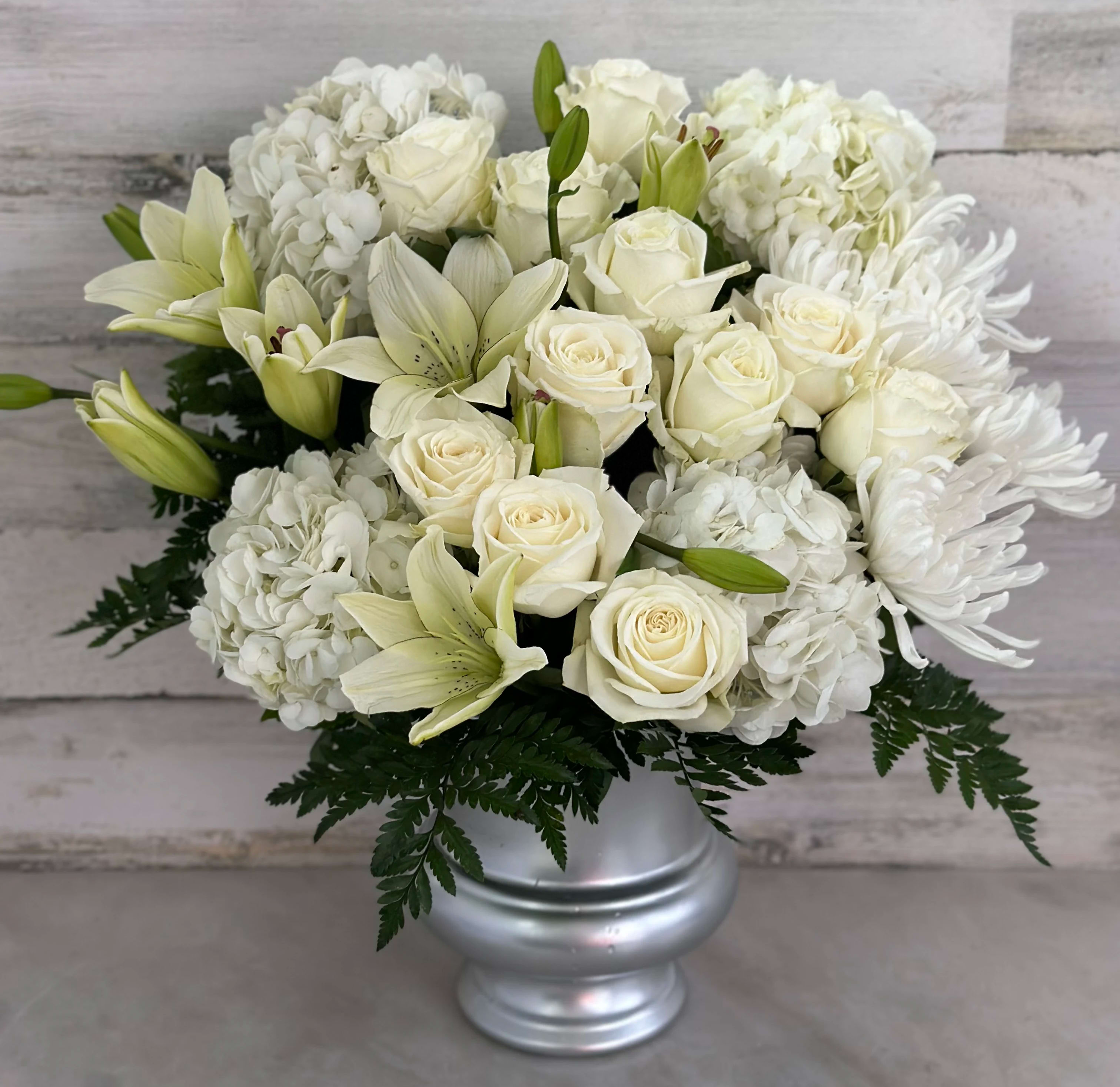 White roses, lilies, hydrangeas, and chrysanthemums in a silver vase