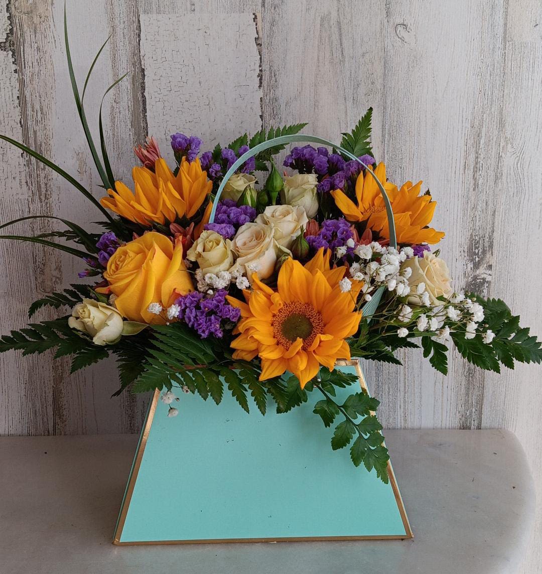 Bouquet of orange sunflowers, cream roses, and purple filler in a turquoise box