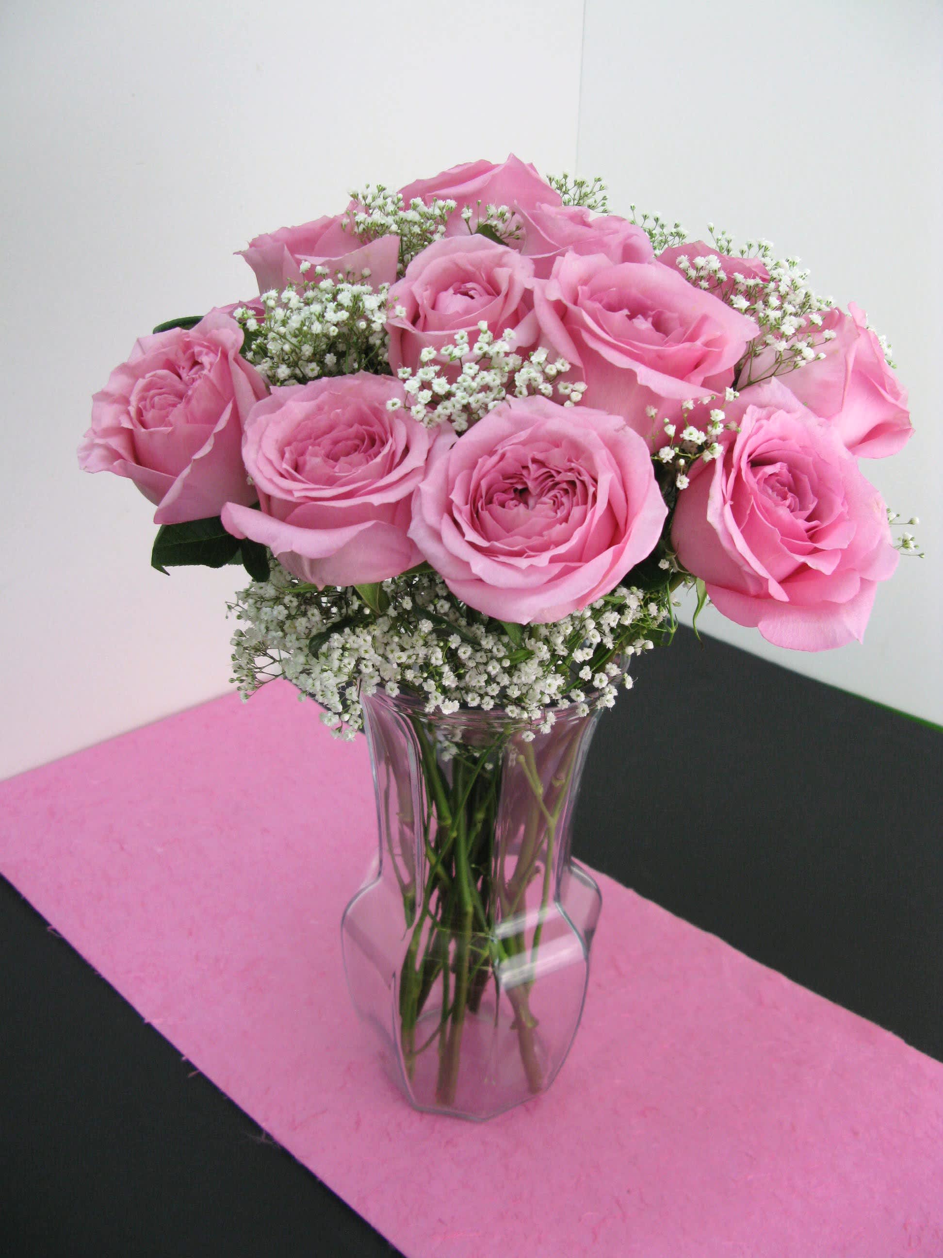 Arrangement of pink roses with white filler flowers in a clear glass vase