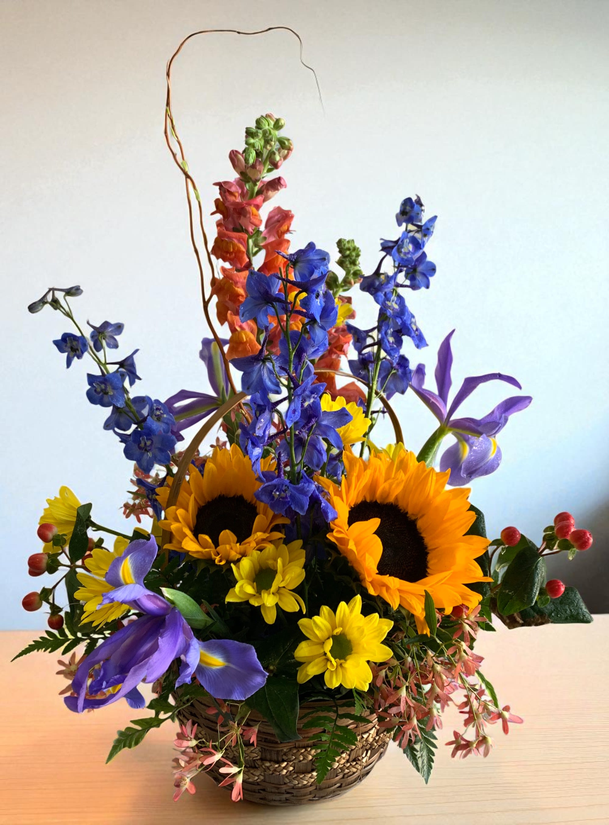 Basket arrangement with sunflowers, blue flowers, and purple irises
