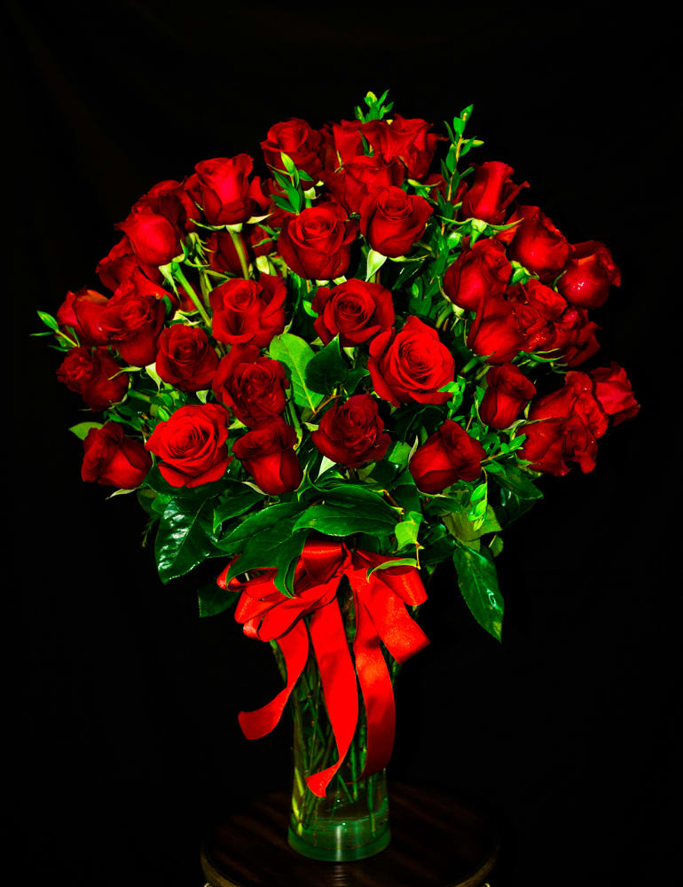 Bouquet of red roses in a clear glass vase with a red ribbon