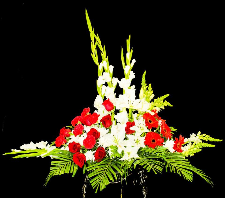 Tall floral arrangement with red roses, white lilies, and orange gerberas