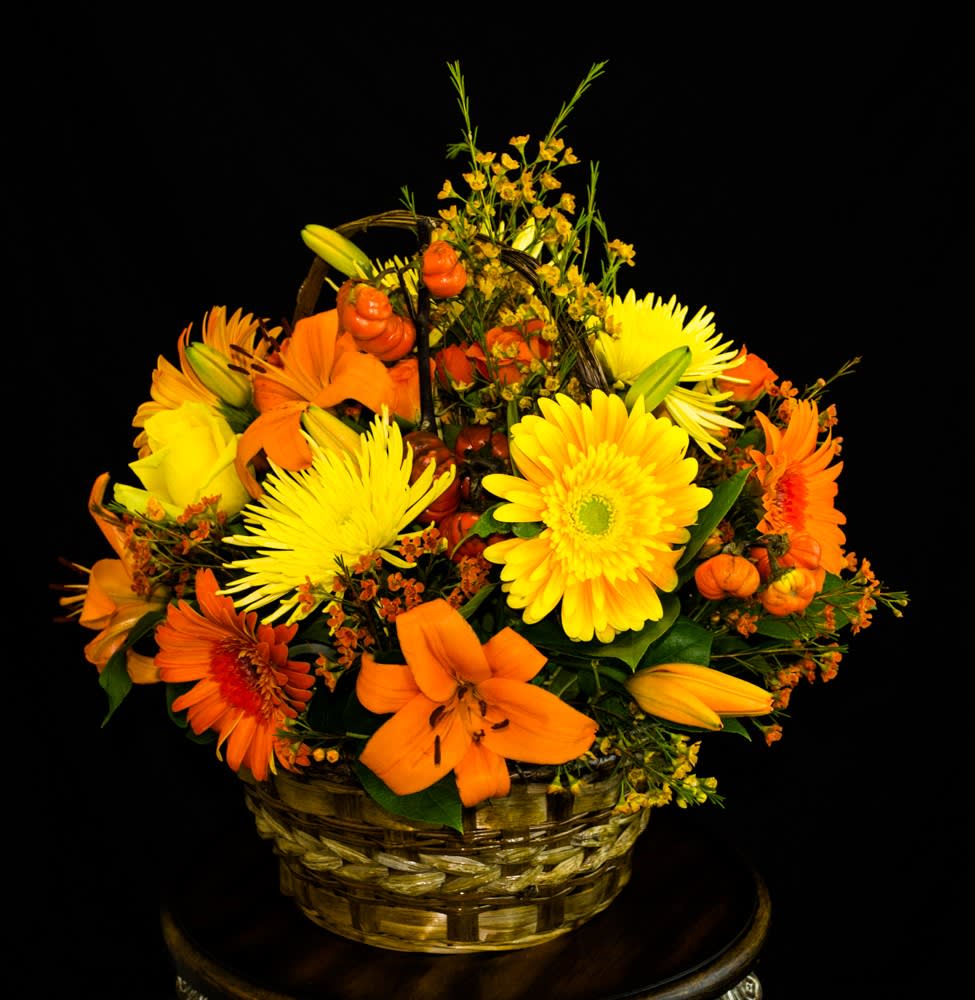 Basket arrangement of yellow and orange flowers with lilies and daisies